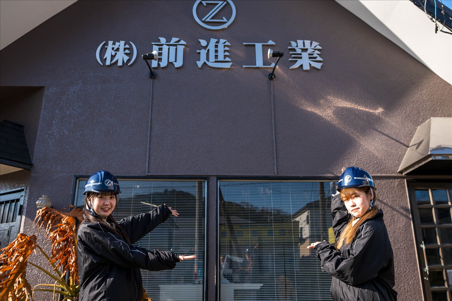 会社看板の前に立つスタッフ
